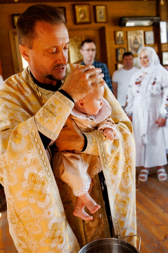 Священник омиває голову немовляти під час хрещення