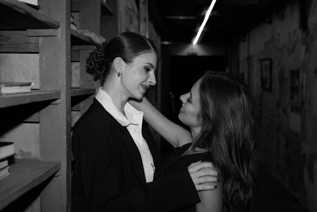 Чорно-білий портрет Маші й Даші, які дивляться одна на одну біля книжкових полиць