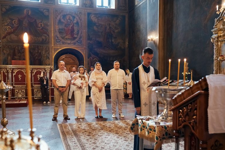 Родина з немовлям стоїть у храмі перед початком хрещення