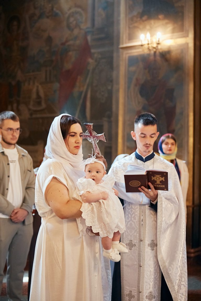 Жінка тримає Софію у білому вбранні поруч зі священником