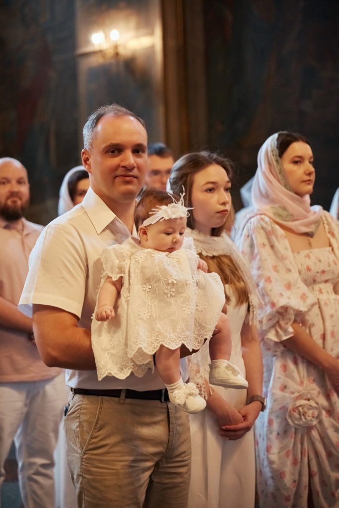 Чоловік тримає немовля під час церемонії хрещення у храмі