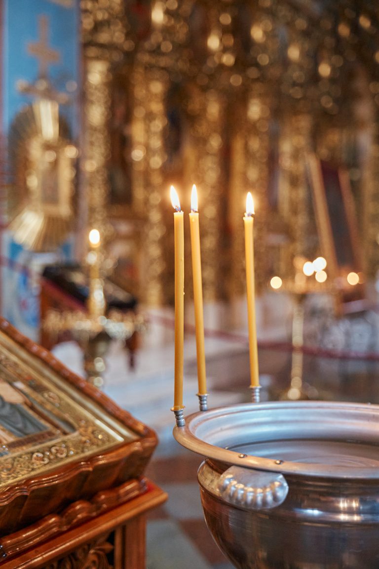 Три запалені свічки біля церковної купелі