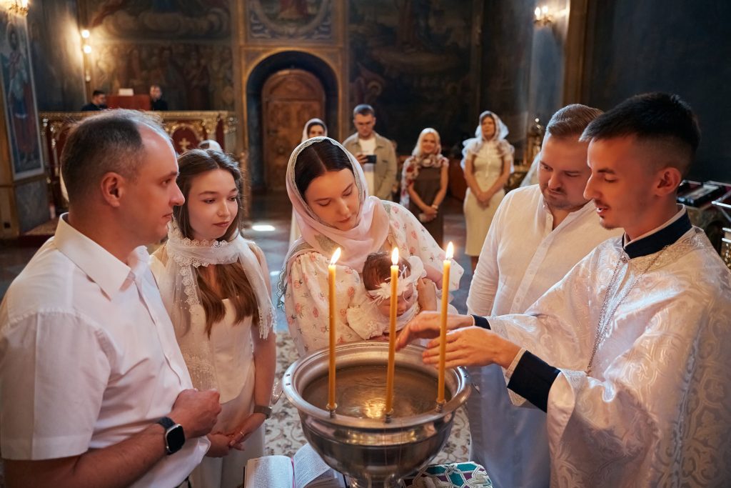 Родина і священник стоять навколо купелі під час хрещення Софії