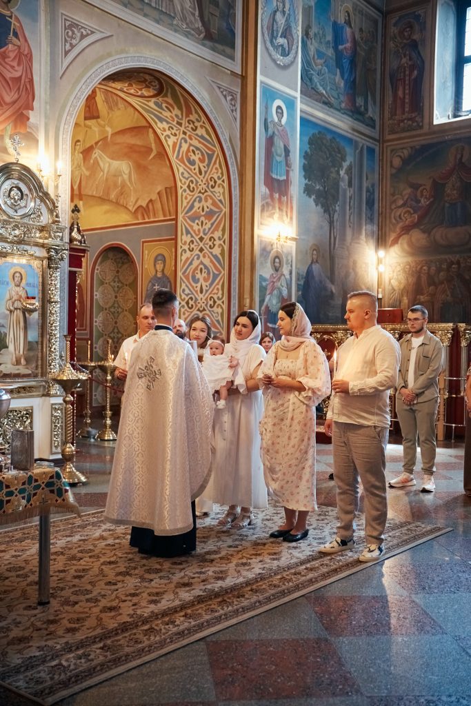 Родина стоїть перед священником у просторому інтер'єрі собору