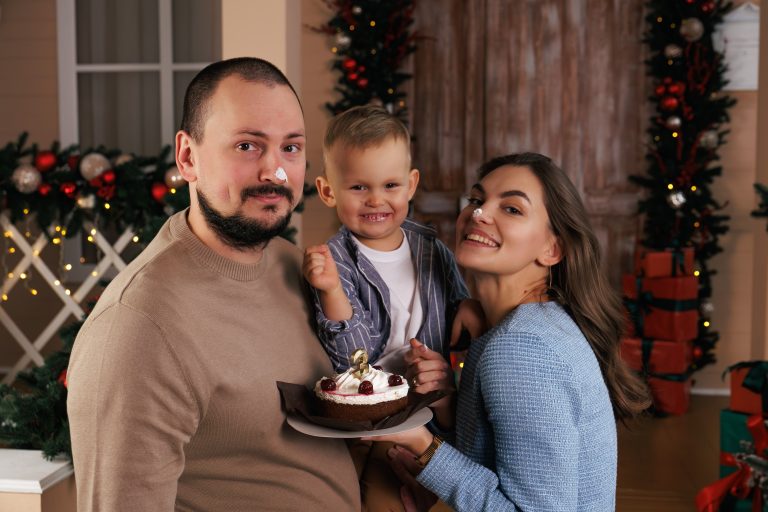 Сім'я позує з тортом на тлі новорічної арки та подарунків