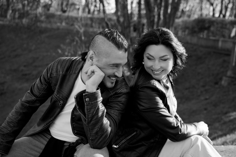 Чорно-білий крупний портрет, де жінка схиляється до чоловіка та торкається його волосся