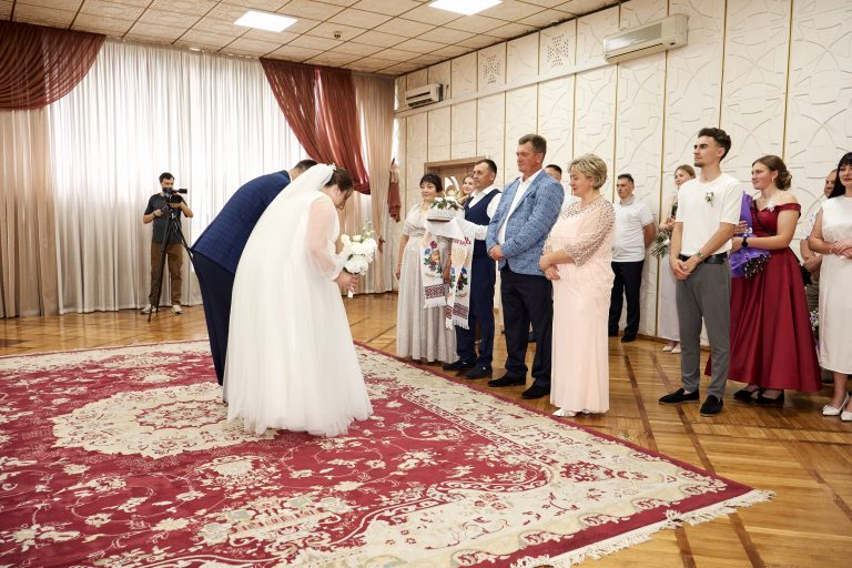 Наталі та Максим вклоняються батькам із весільним короваєм у залі РАЦСу