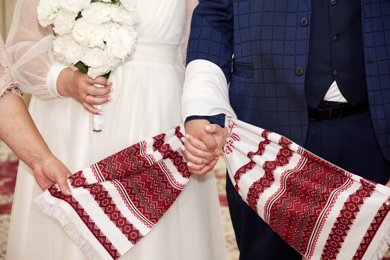 Наталі та Максим усміхаються і показують весільні обручки після розпису