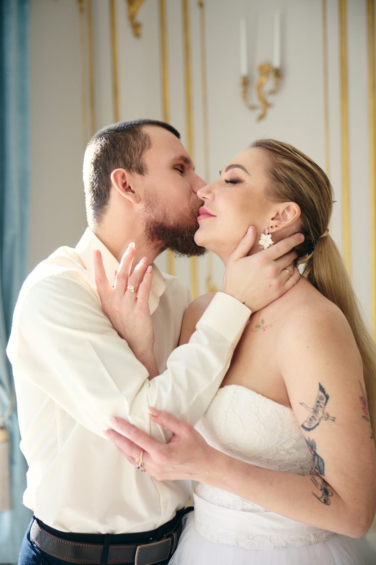 Наречений ніжно цілує наречену у щоку під час весільної фотосесії