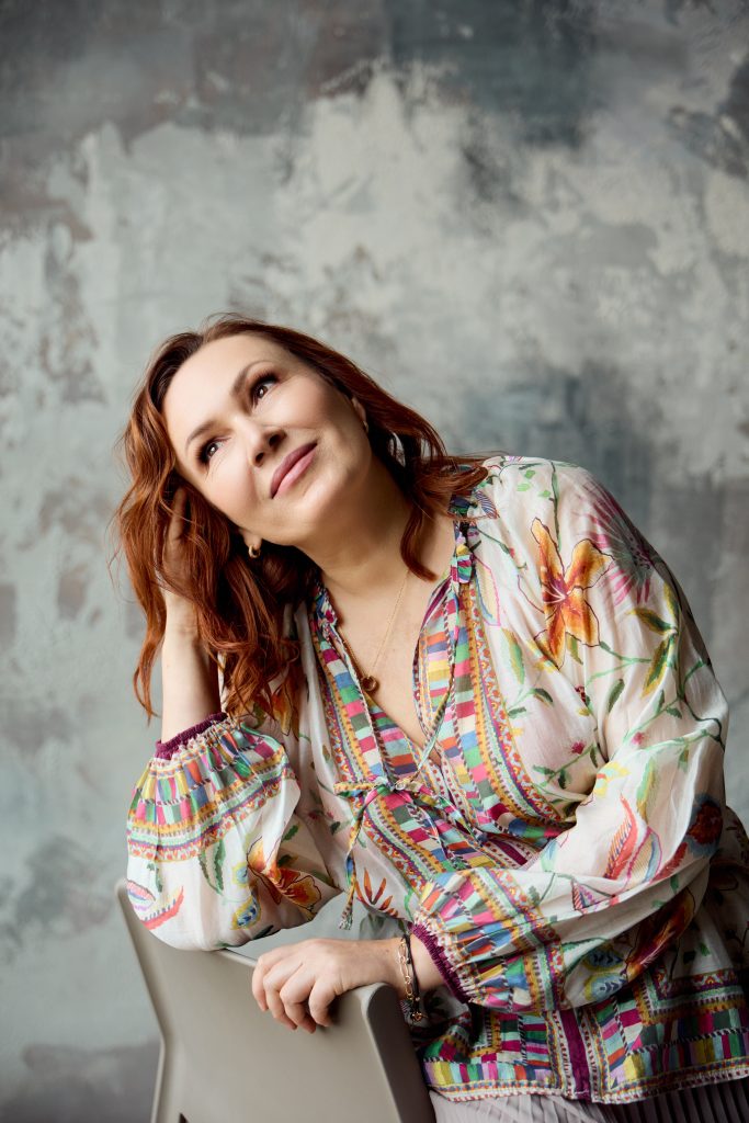 Вікторія спирається на стілець і дивиться вгору на тлі сірої декоративної стіни