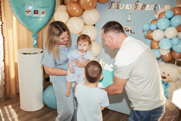 Родина біля святкової фотозони готується винести торт для іменинника