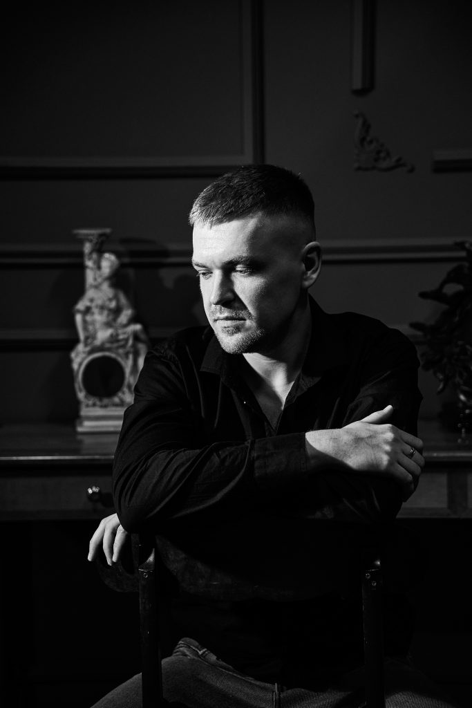 Чорно-білий чоловічий портрет Дмитра, який сидить у кріслі та дивиться вбік