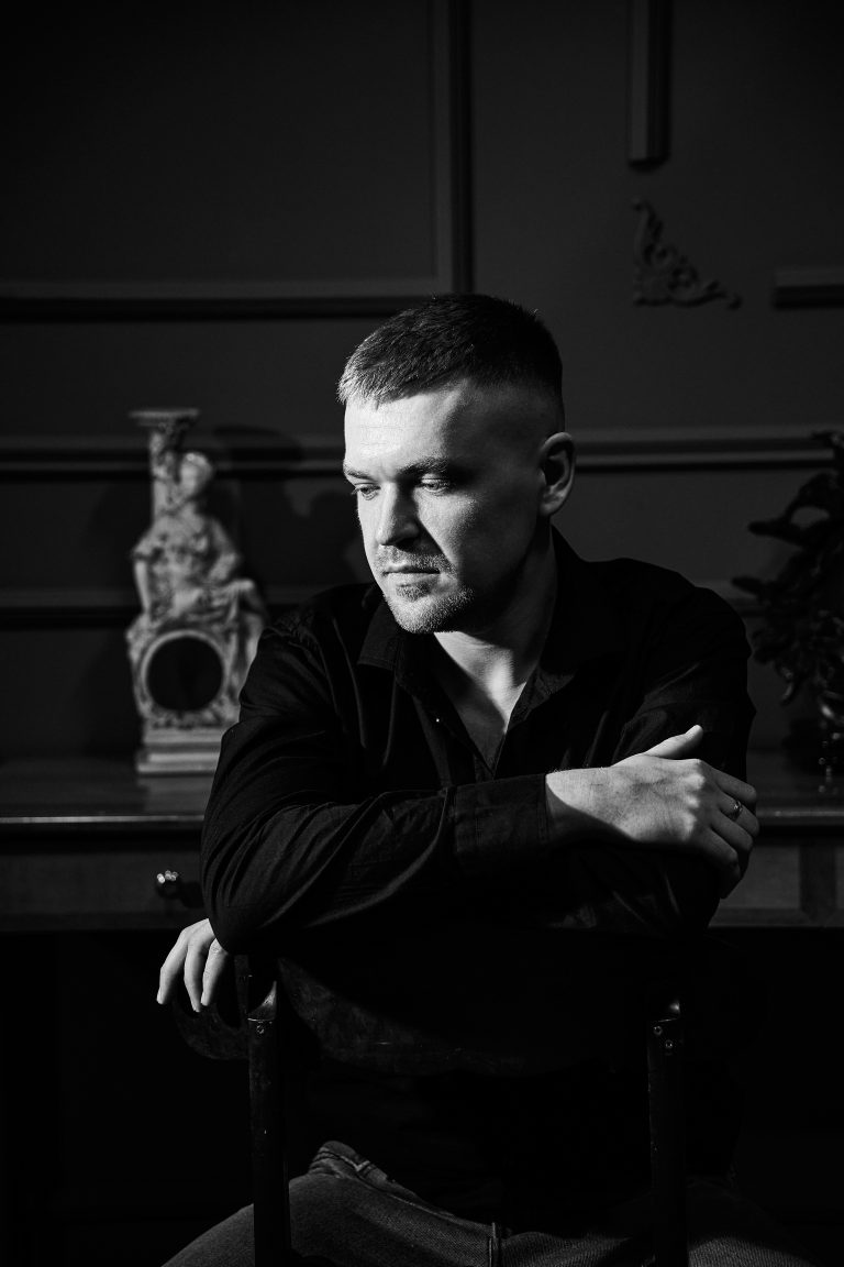 Чорно-білий чоловічий портрет Дмитра, який сидить у кріслі та дивиться вбік