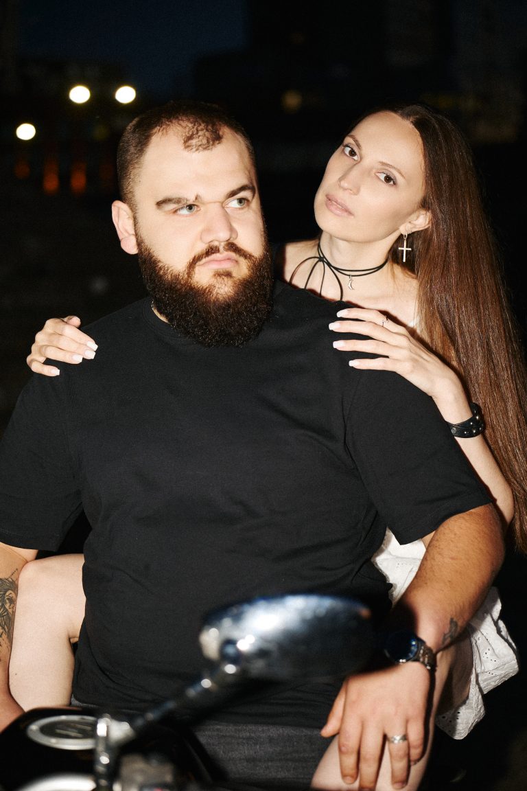 Нічний портрет чоловіка і жінки біля мотоцикла зі спалахом та темним фоном
