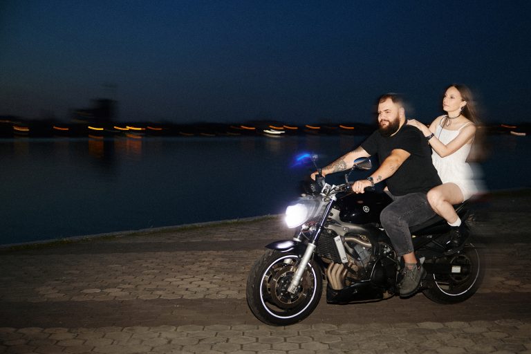 Чоловік і жінка їдуть на мотоциклі вздовж нічної набережної з ефектом руху