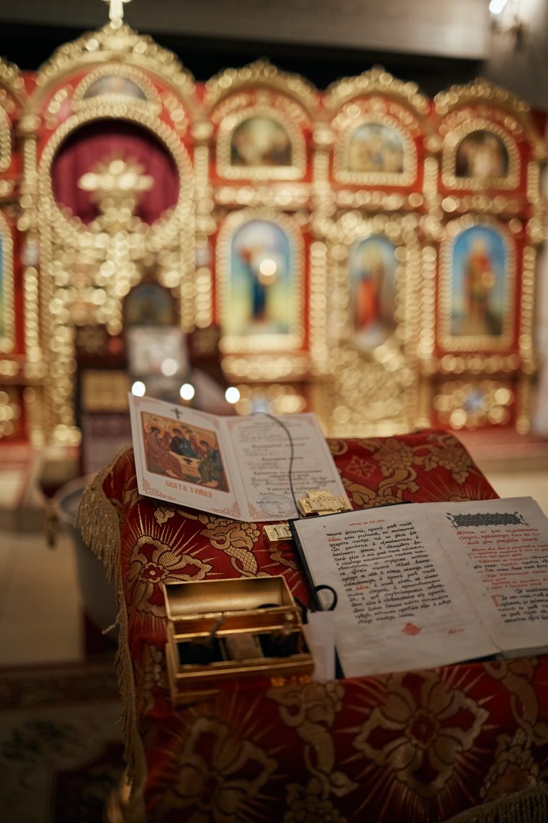 Церковні книги та свідоцтво про хрещення на червоному аналойному покритті перед іконостасом