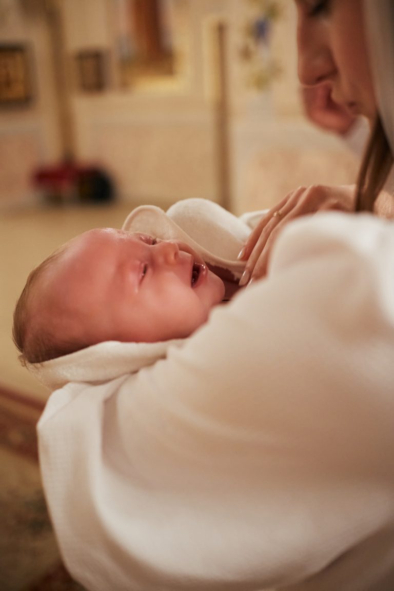 Немовля Емілія плаче на руках у жінки в білому одязі всередині храму