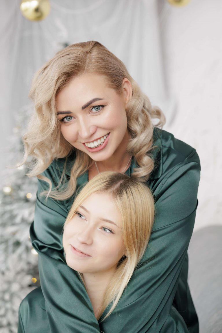 Наталі ніжно обіймає Аріну зверху у світлій новорічній студії