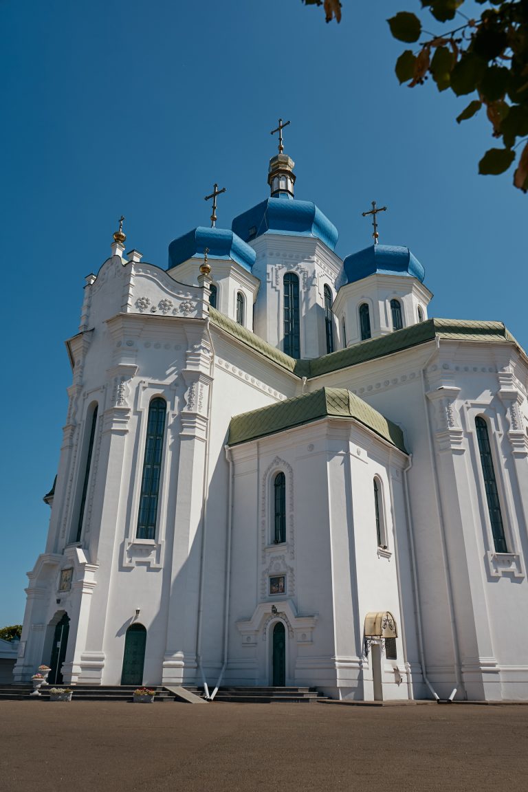 Зовнішній вигляд білого Свято-Троїцького Храму УПЦ з блакитними куполами у сонячний день
