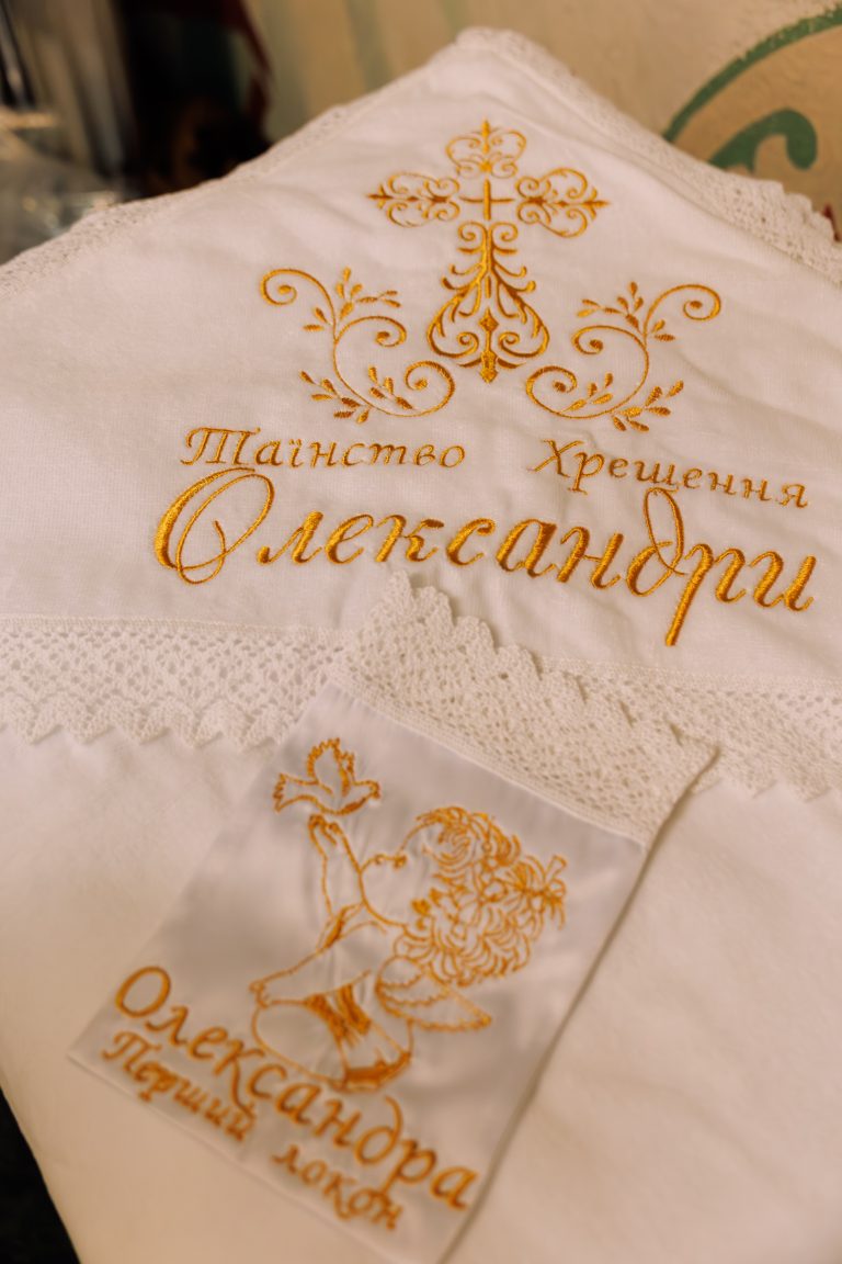 Білий хрестильний рушник з іменем Олександра та золотистою вишивкою хреста