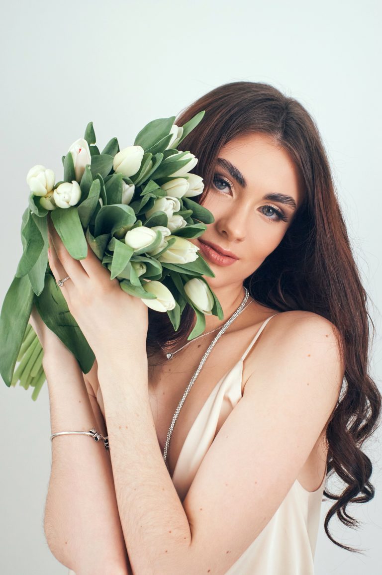Анна тримає букет білих тюльпанів біля обличчя на світлому фоні