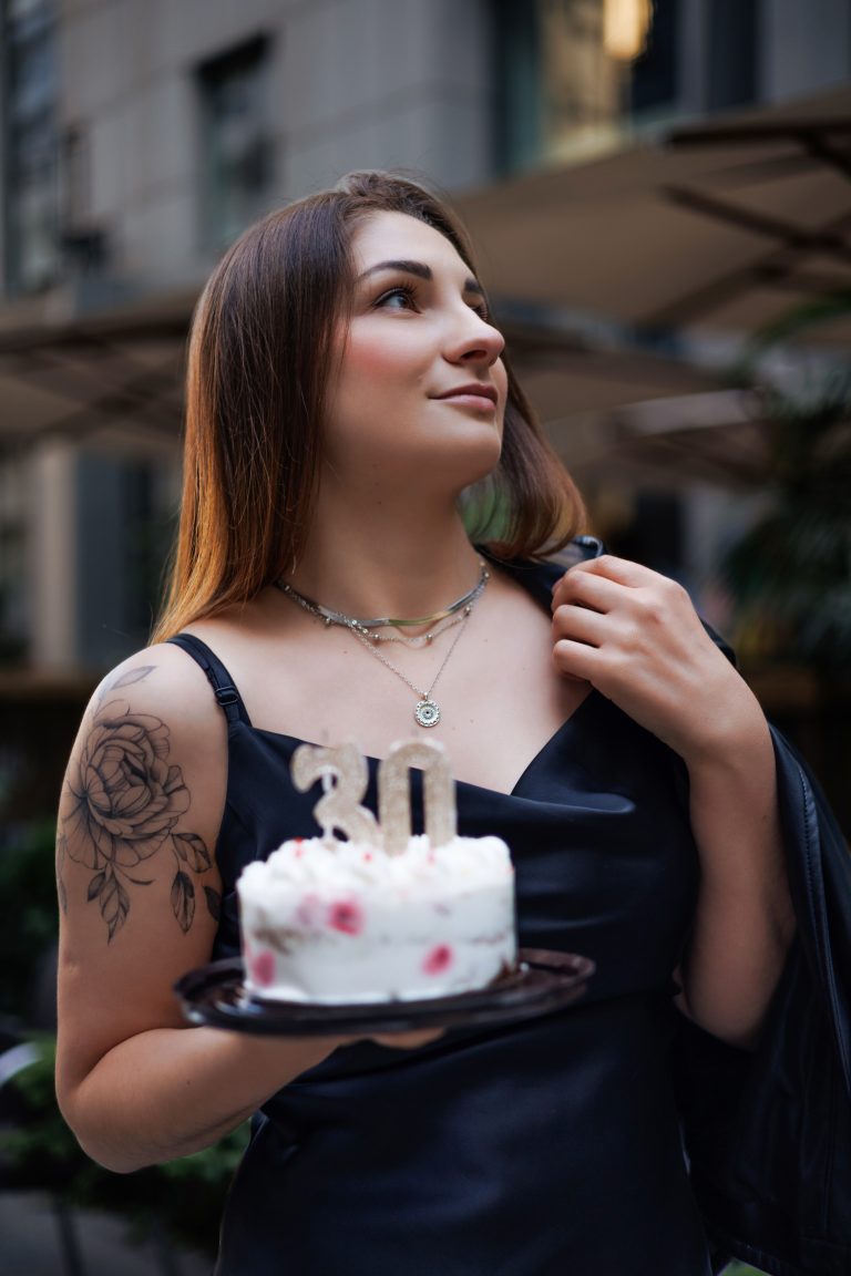 Маргарита у чорній сукні тримає торт зі свічками у формі числа 30
