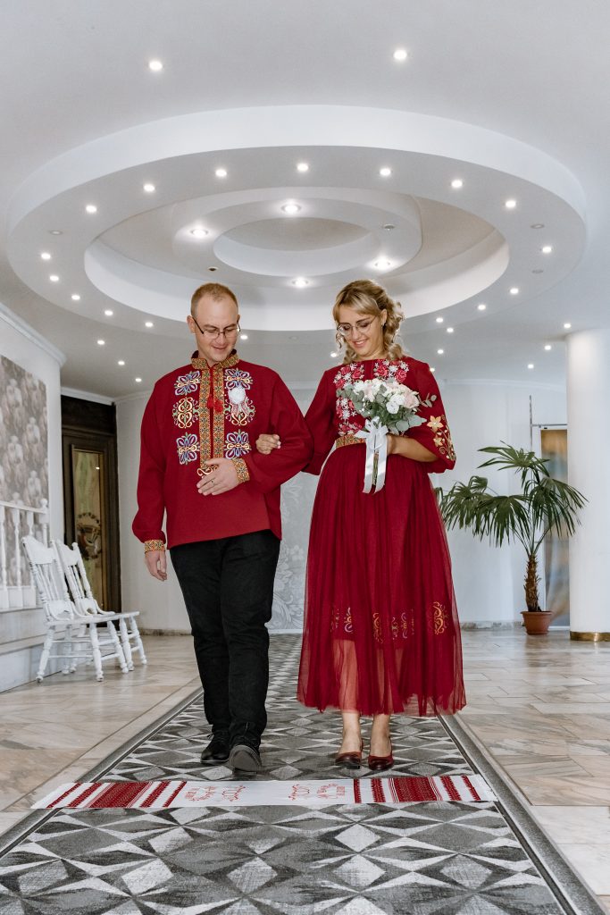 Марина та Ігор проходять церемоніальним проходом у залі РАЦСу, тримаючись під руку