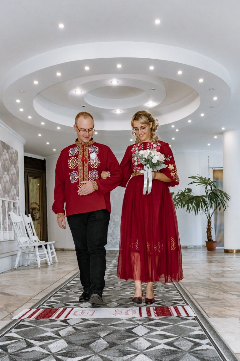 Марина та Ігор проходять церемоніальним проходом у залі РАЦСу, тримаючись під руку