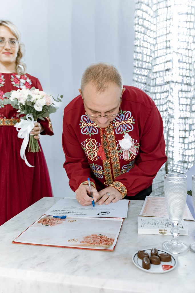 Ігор підписує документи про шлюб у Дніпровському РАЦСі, Марина стоїть поруч з букетом