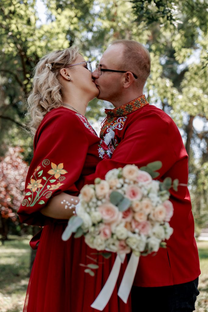 Марина та Ігор цілуються у парку, а весільний букет розташований на передньому плані