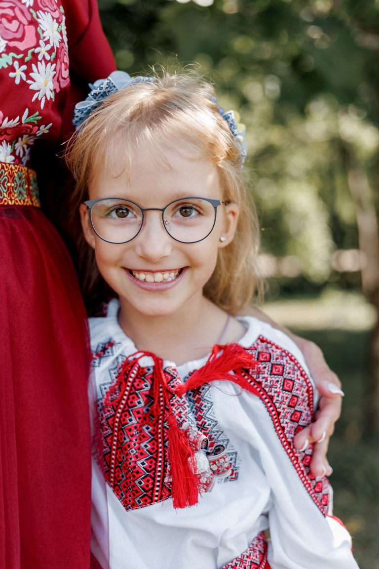 Портрет усміхненої Веронічки в окулярах і вишиванці на фоні зеленого парку