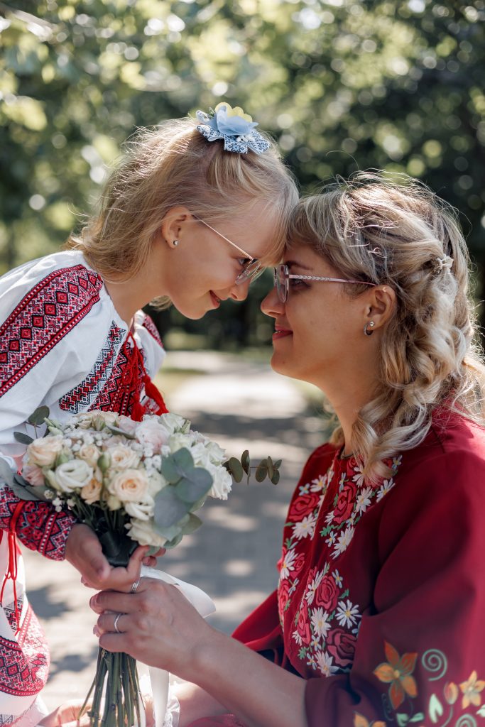 Марина та Веронічка торкаються лобами, тримаючи весільний букет у сонячному парку