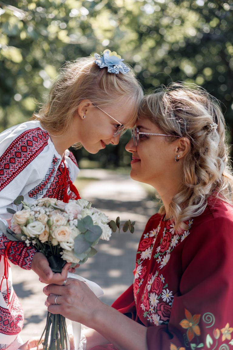 Марина та Веронічка торкаються лобами, тримаючи весільний букет у сонячному парку