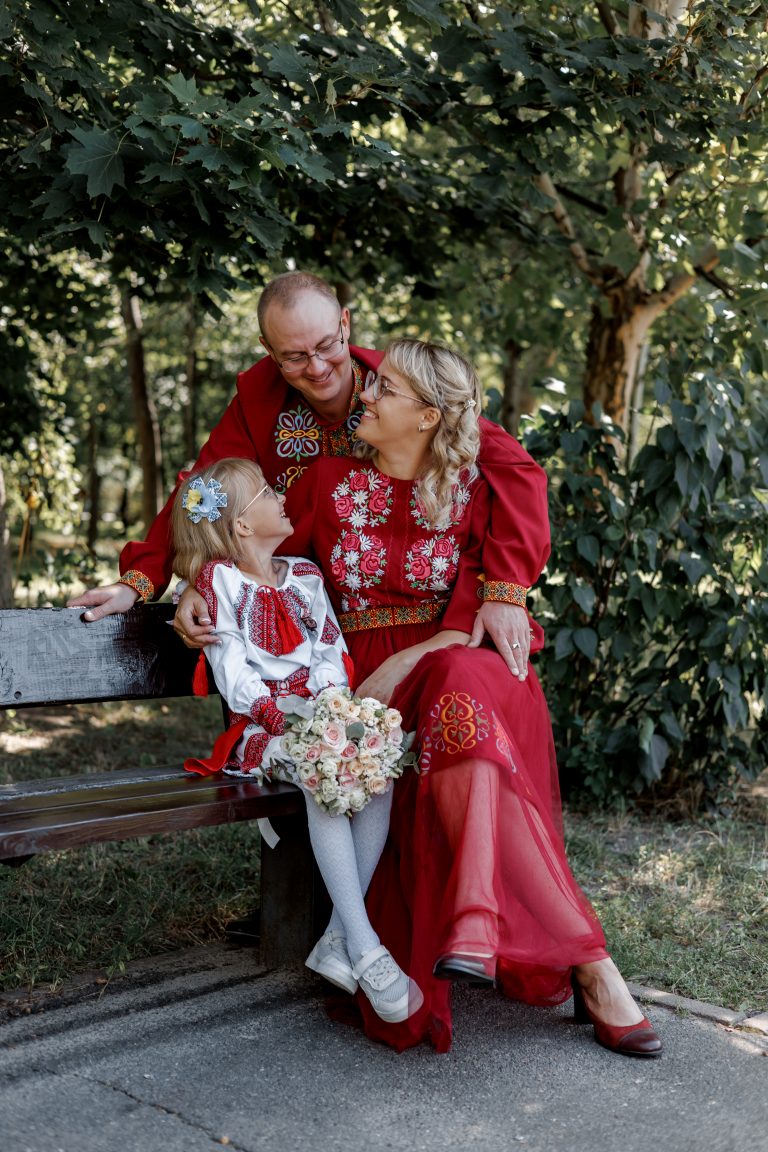 Марина, Ігор і Веронічка сидять разом на лавці у зеленій частині парку
