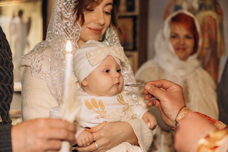 Священник проводить частину обряду біля обличчя Уляни, яку тримає жінка