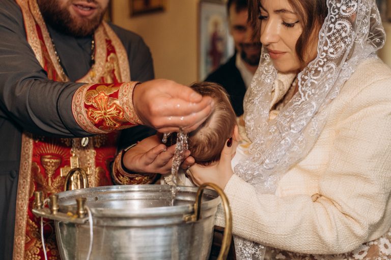 Священник поливає голову Уляни водою над хрестильною купіллю