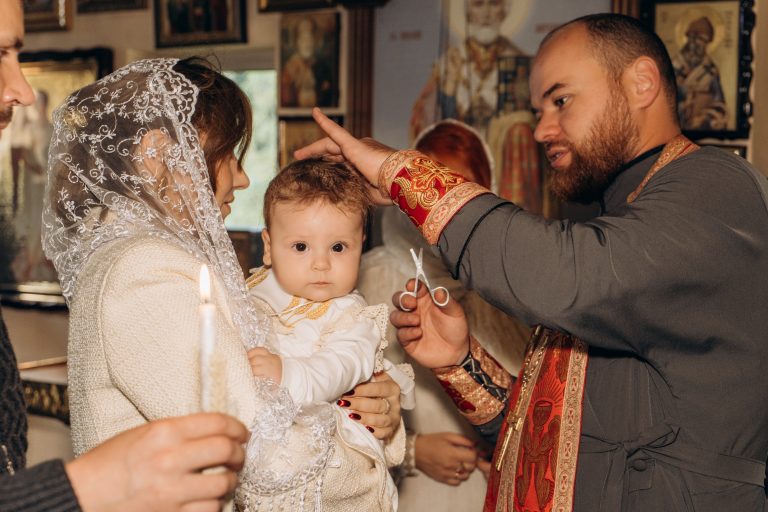 Священник із маленькими ножицями проводить обряд біля голови Уляни