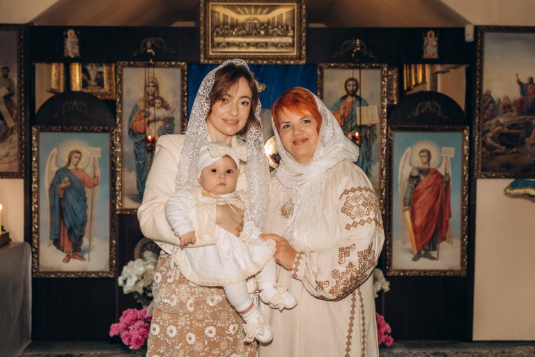 Дві жінки позують у храмі з Уляною на руках на тлі ікон