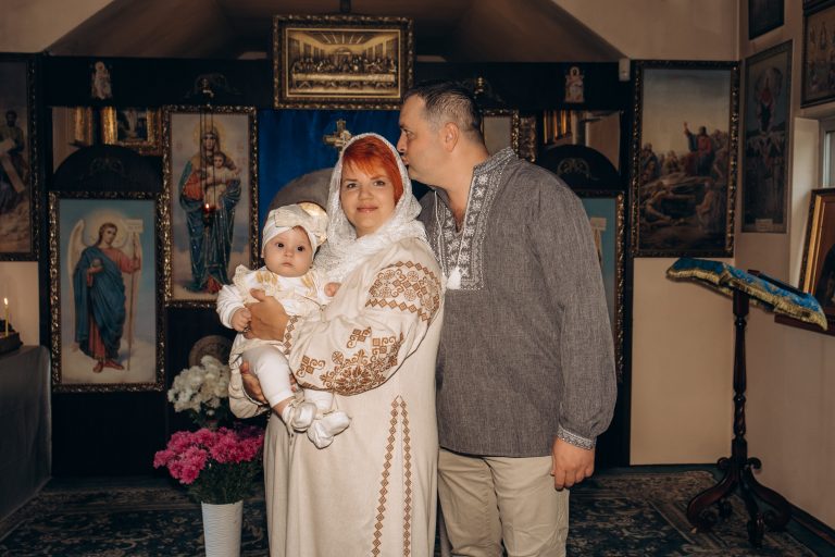 Жінка тримає Уляну на руках, а чоловік ніжно цілує жінку в голову в храмі
