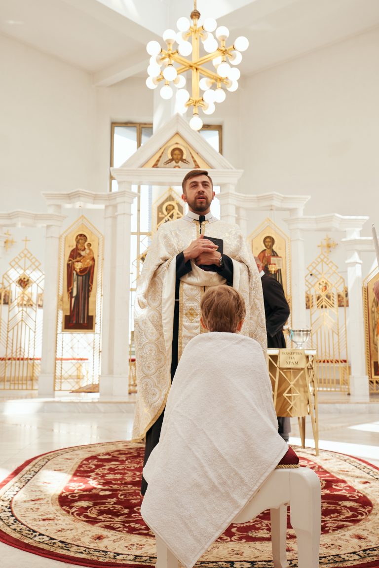 Священник молиться перед Ярославом, загорнутим у білий рушник, на тлі іконостаса