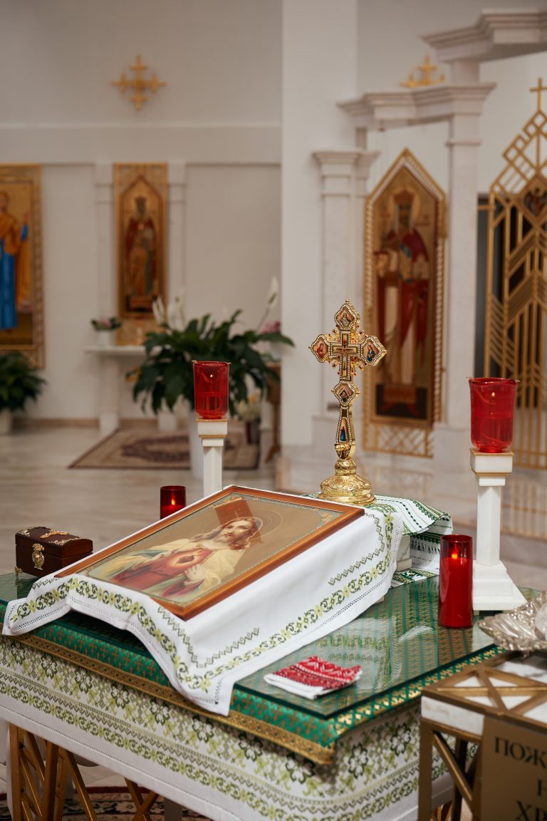 Хрест, ікона та запалені червоні лампади на столі для церемонії хрещення