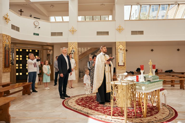 Священник читає молитву під час хрещення Ярослава, поруч стоять присутні