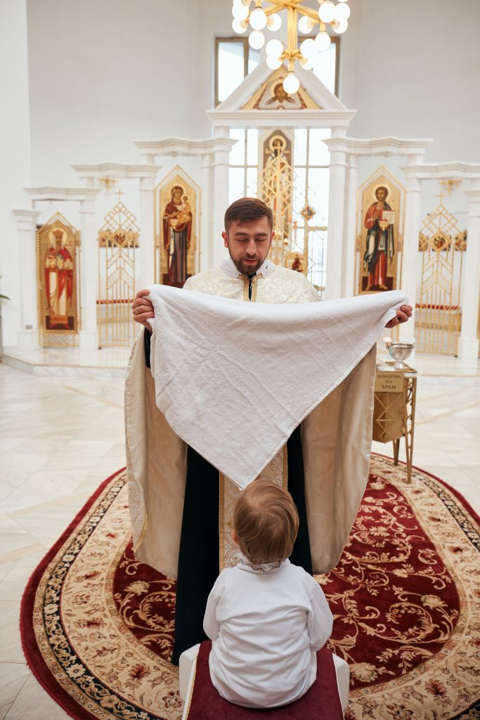 Священник тримає білий рушник перед Ярославом після обливання водою