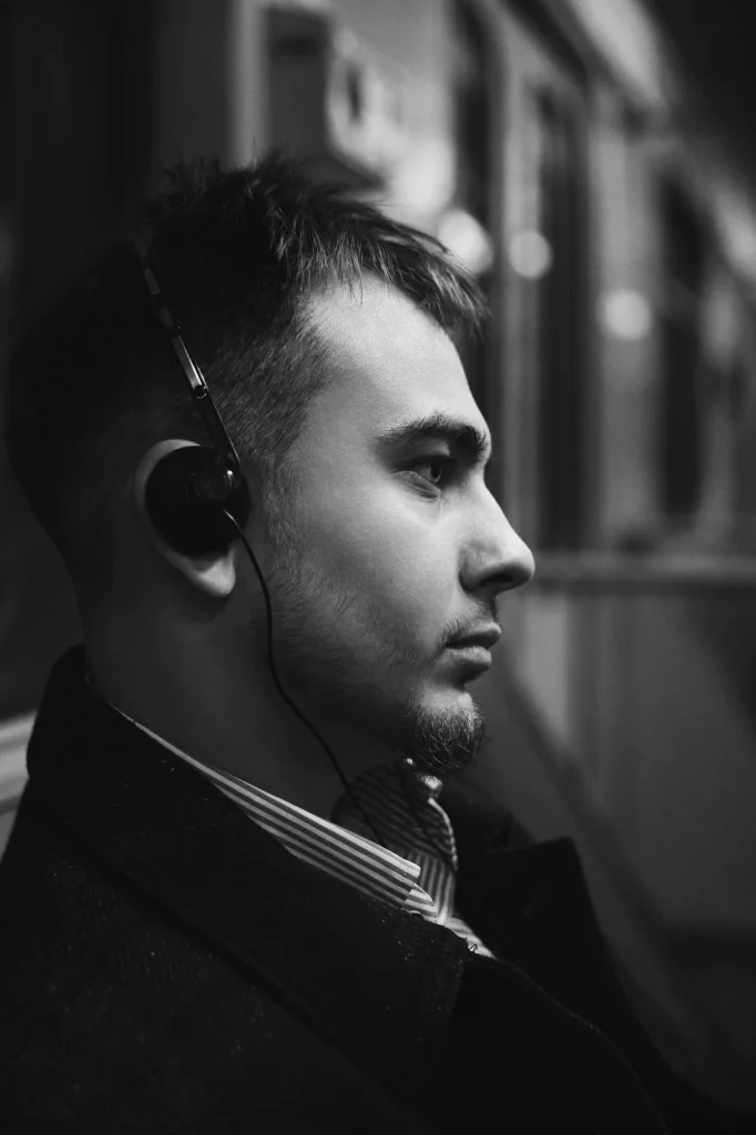 Чорно-білий крупний профіль Арсена в навушниках у вагоні метро, сорочка в смужку, Київ