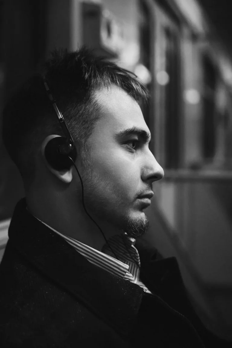 Чорно-білий крупний профіль Арсена в навушниках у вагоні метро, сорочка в смужку, Київ