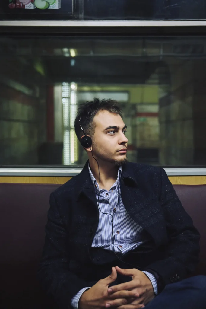 Арсен у пальті й сорочці в смужку сидить біля вікна вагона, склавши руки, дивиться вбік, Київ