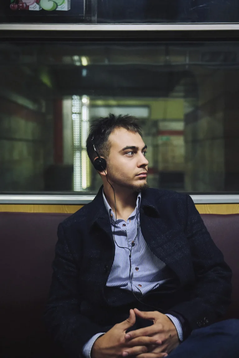 Арсен у пальті й сорочці в смужку сидить біля вікна вагона, склавши руки, дивиться вбік, Київ