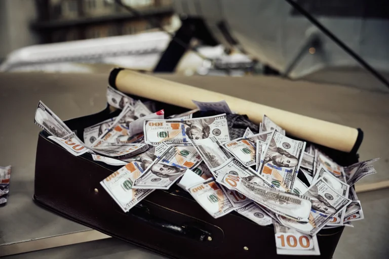 Відкрита валіза, повна купюр по 100 доларів, і тубус на крилі літака в ангарі, деталь арт-зйомки, Київ